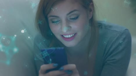 Animation-of-green-molecules-over-happy-caucasian-woman-using-smartphone