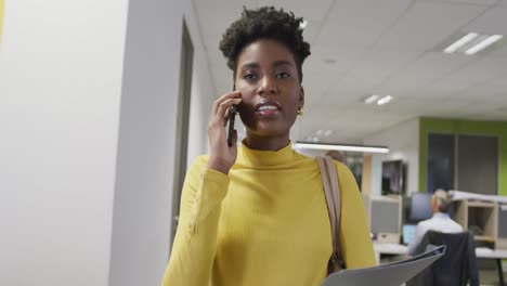 Glückliche-Afroamerikanische-Geschäftsfrau,-Die-Auf-Dem-Smartphone-Spricht-Und-Im-Büro-Spaziert