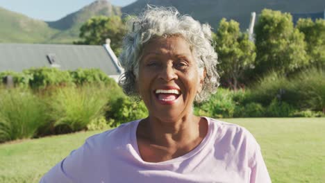 Portrait-of-happy-senior-african-american-woman-in-garden-on-sunny-day-at-retirement-home