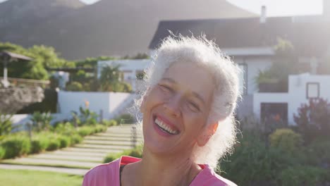 Portrait-of-happy-senior-biracial-woman-in-garden-on-sunny-day-at-retirement-home