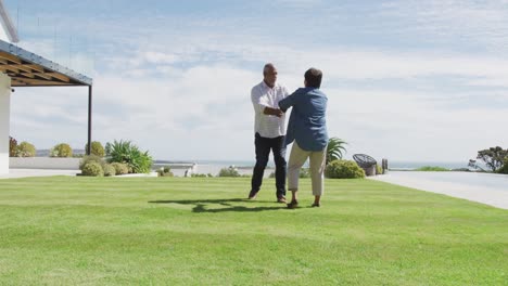 Happy-senior-diverse-couple-dancing-in-garden-at-retirement-home