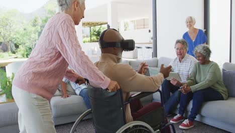 Glückliche-ältere,-Vielfältige-Menschen-Mit-Einem-Mann-Im-Rollstuhl,-Der-Im-Altersheim-Ein-VR-Headset-Verwendet