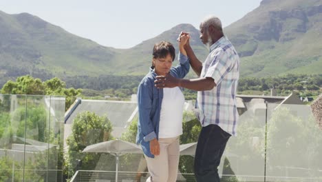 Happy-senior-diverse-couple-dancing-on-balcony-at-retirement-home