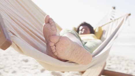 Happy-african-american-woman-lying-in-hammock-on-sunny-beach