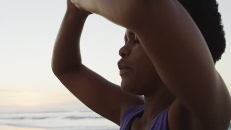 Mujer-Afroamericana-Practicando-Yoga-Y-Meditando-En-La-Playa-Soleada