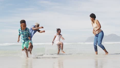 Glückliches-Afroamerikanisches-Paar,-Das-Mit-Kindern-Am-Sonnigen-Strand-Spielt