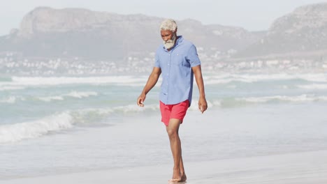 Hombre-Afroamericano-Mayor-Caminando-Solo-En-La-Playa-Soleada