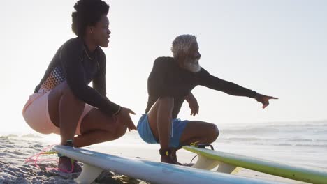 Glückliches-Afroamerikanisches-Paar-Mit-Surfbrettern-Am-Sonnigen-Strand