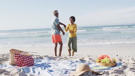 Glückliches-Afroamerikanisches-Paar-Beim-Picknick-Und-Tanzen-Am-Sonnigen-Strand