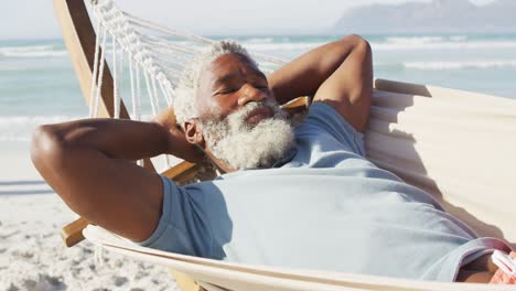 Glücklicher-älterer-Afroamerikanischer-Mann,-Der-In-Der-Hängematte-Am-Sonnigen-Strand-Liegt