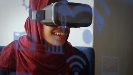 Animation-Digitaler-Symbole-über-Einer-Birazialen-Frau-Im-Hijab,-Die-Ein-VR-Headset-Trägt