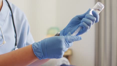 Video-of-hands-of-biracial-female-doctor-preparing-vaccine