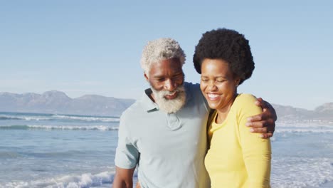 Glückliches-Afroamerikanisches-Paar,-Das-Am-Sonnigen-Strand-Spaziert-Und-Sich-Umarmt