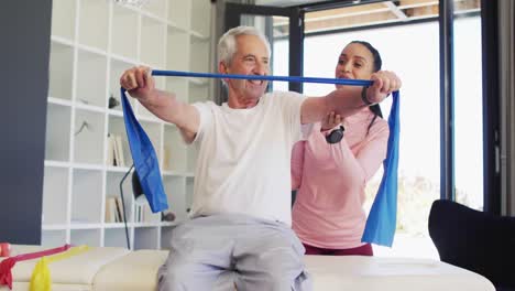 Video-of-happy-biracial-female-physiotherapist-exercising-with-caucasian-senior-man