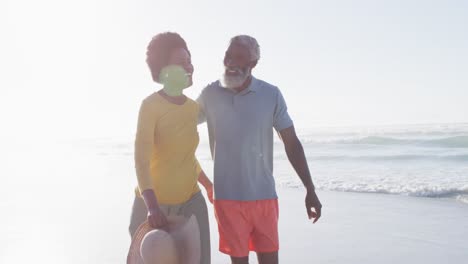 Happy-african-american-couple-walking-and-talking-on-sunny-beach
