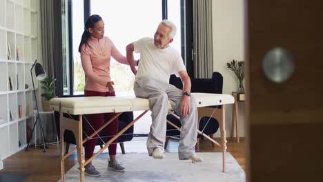 Video-of-biracial-female-physiotherapist-examining-caucasian-senior-man