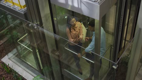 Video-of-diverse-businesswoman-and-businessman-talking-in-elevator