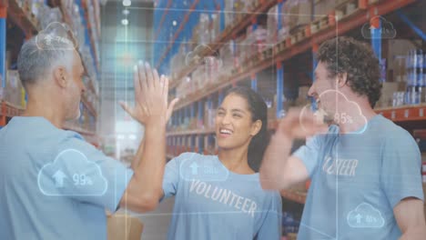 Animation-of-clouds-and-data-processing-over-diverse-volunteers-high-fiving-in-warehouse