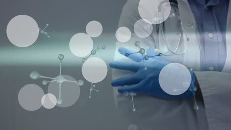 Animation-of-floating-white-dots-over-midsection-of-female-doctor-in-medical-gloves
