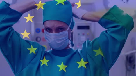 Animation-of-flag-of-european-union-over-caucasian-female-surgeon-tying-face-mask
