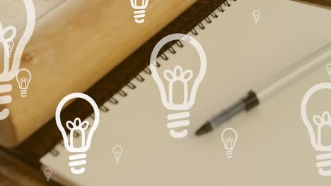 Animation-of-lightbulb-icons-over-notebook-and-pen