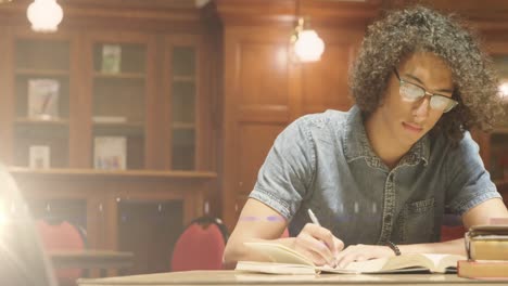 Animation-of-light-over-biracial-man-writing-in-notebook