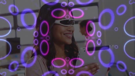 Animation-of-neon-shapes-over-biracial-woman-using-vr-glasses-and-tablet