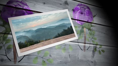 Photograph-of-landscape-with-woods-and-mountains-against-floral-print-on-wooden-background