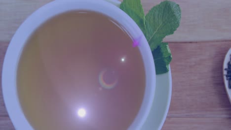 Animation-Von-Lichtflecken-über-Einer-Tasse-Tee-Auf-Dem-Tisch