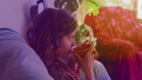 Animation-Von-Lichtflecken-über-Einer-Biracial-Frau,-Die-Zu-Hause-Kaffee-Trinkt