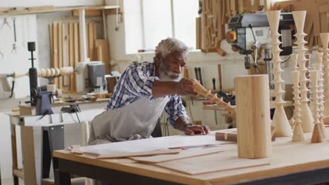 Afroamerikanischer-Tischler,-Der-In-Einer-Tischlerei-Ein-Holzhandwerk-Auf-Dem-Werkstatttisch-Hält