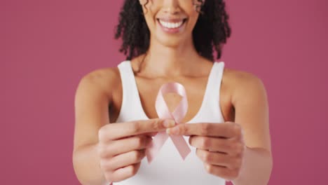 Video-of-smiling-biracial-woman-holding-pink-breast-cancer-ribbon