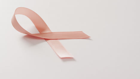 Video-of-peach-pink-uterine-cancer-ribbon-on-white-background