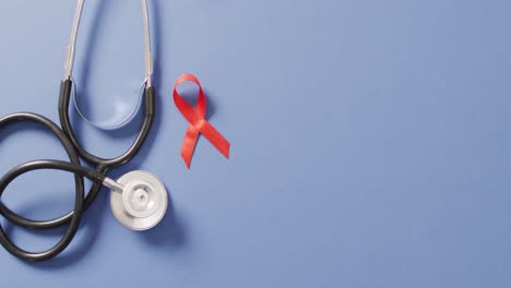 Video-of-stethoscope-and-red-blood-cancer-ribbon-on-blue-background