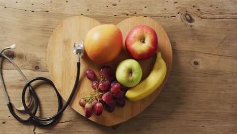 Video-of-close-up-of-stethoscope-with-fruit-on-wooden-table