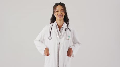 Video-of-portrait-of-smiling-biracial-female-doctor-on-white-background