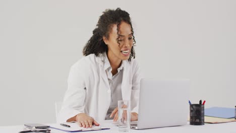 Video-of-smiling-biracial-female-doctor-having-laptop-video-call