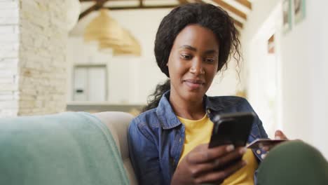 Video-of-happy-african-american-woman-on-sofa-using-smartphone
