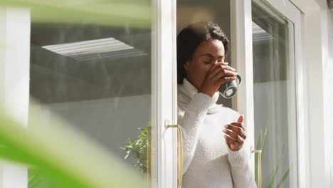 Video-Einer-Glücklichen-Und-Entspannten-Afroamerikanischen-Frau,-Die-Auf-Der-Terrasse-Kaffee-Trinkt