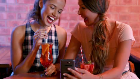 Animation-of-beer-icons-over-happy-caucasian-female-friends-using-smartphone