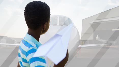 Animation-Eines-Glücklichen-Afroamerikanischen-Jungen,-Der-Mit-Einem-Papierflieger-über-Einem-Flugzeug-Spielt