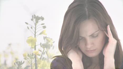 Composite-video-of-stressed-caucasian-woman-against-yellow-flowers-moving-in-the-wind