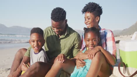 Porträt-Einer-Afroamerikanischen-Familie,-Die-Lächelt,-Während-Sie-Am-Strand-Sitzt