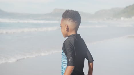 Afroamerikanischer-Kleiner-Junge,-Der-Am-Strand-Springt-Und-Genießt
