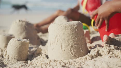 Mittelteil-Eines-Afroamerikanischen-Mädchens,-Das-Am-Strand-Mit-Sand-Spielt