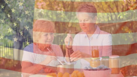Animation-of-flag-of-usa-over-senior-caucasian-female-friends-eating-dinner-outdoors