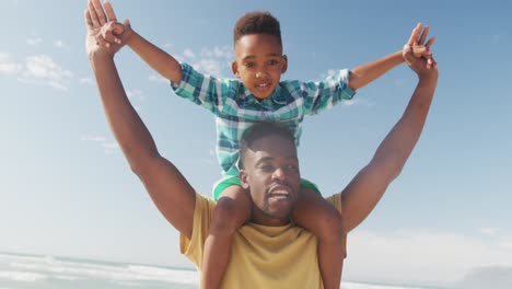 Afroamerikanischer-Vater-Trägt-Seinen-Sohn-Auf-Seinen-Schultern-Am-Strand