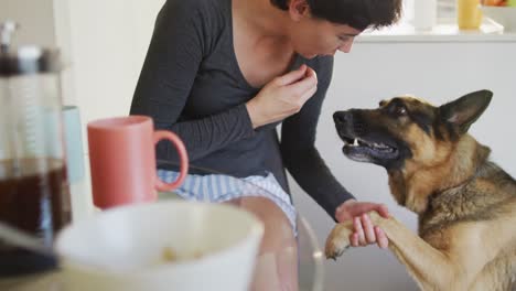 Kaukasische-Frau-Füttert-Und-Küsst-Ihren-Hund-Im-Wohnzimmer-Zu-Hause