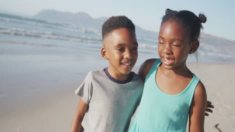 Portrait-of-african-american-brother-and-sister-hugging-each-other-at-the-beach