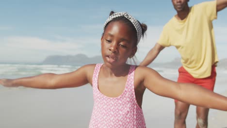 African-american-father-and-daughter-with-arms-wide-open-enjoying-at-the-beach